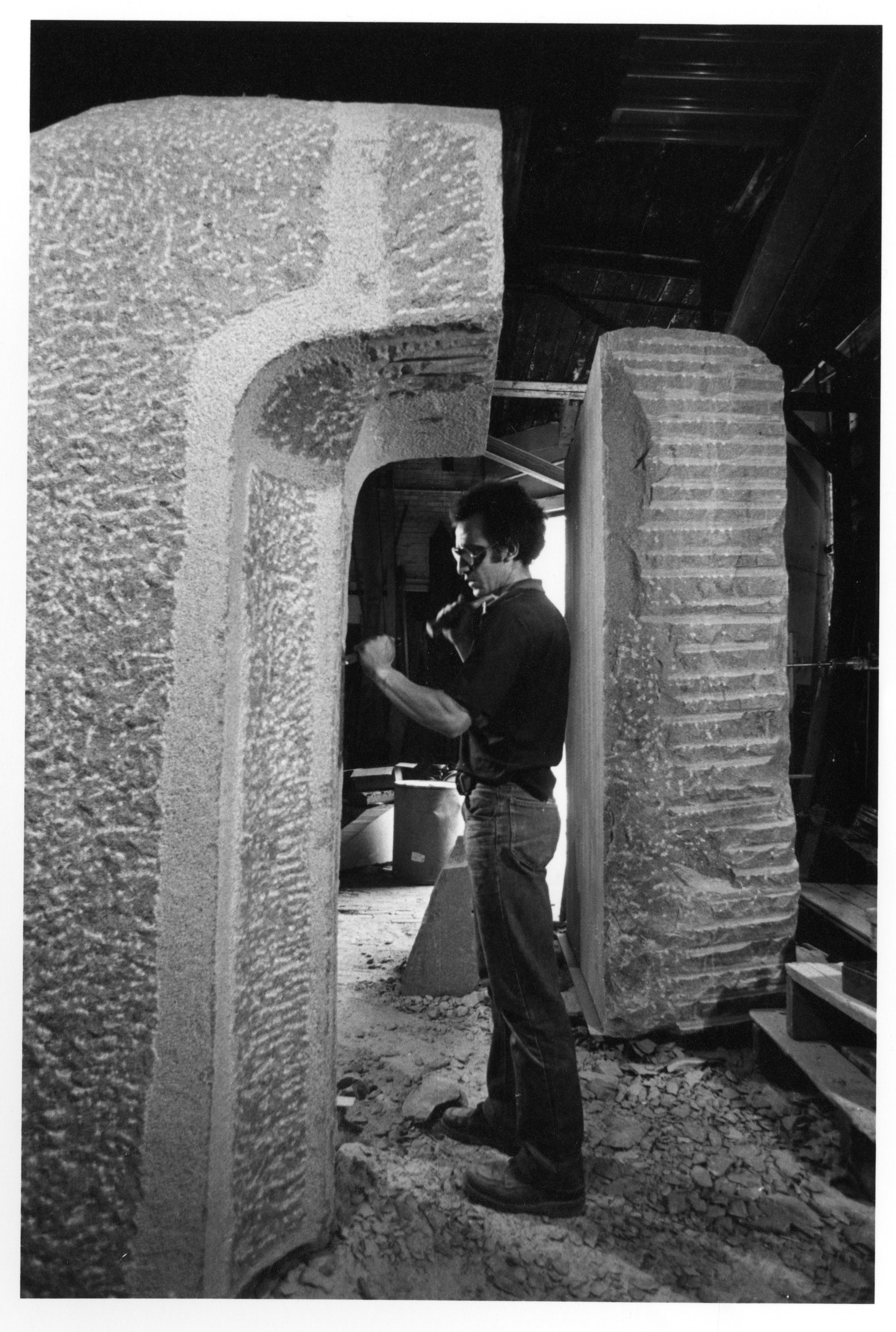 Artist Carlos Dorrien works on the "Portal" sculpture by carving large pieces of Laurentian granite.